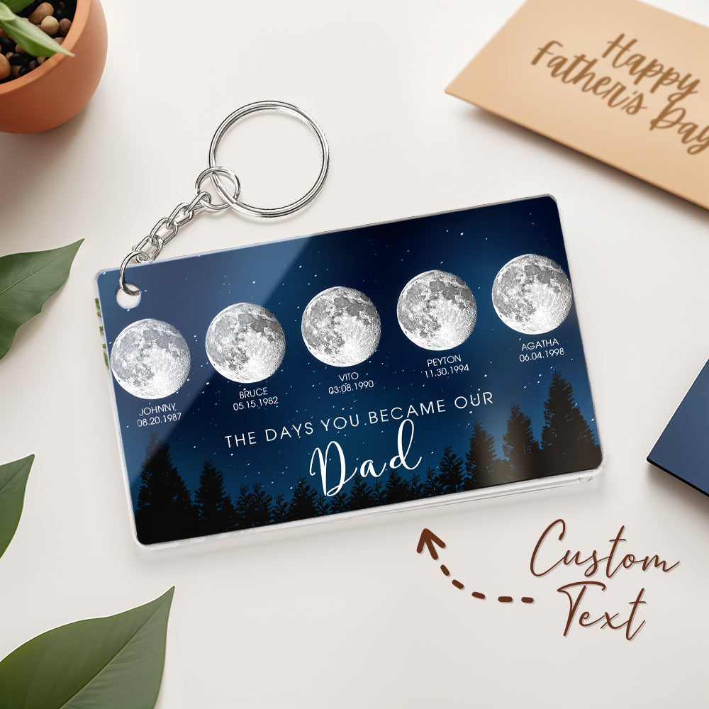 Keychain with moon phases and personalized text on a white surface with a 'Happy Father's Day' card.