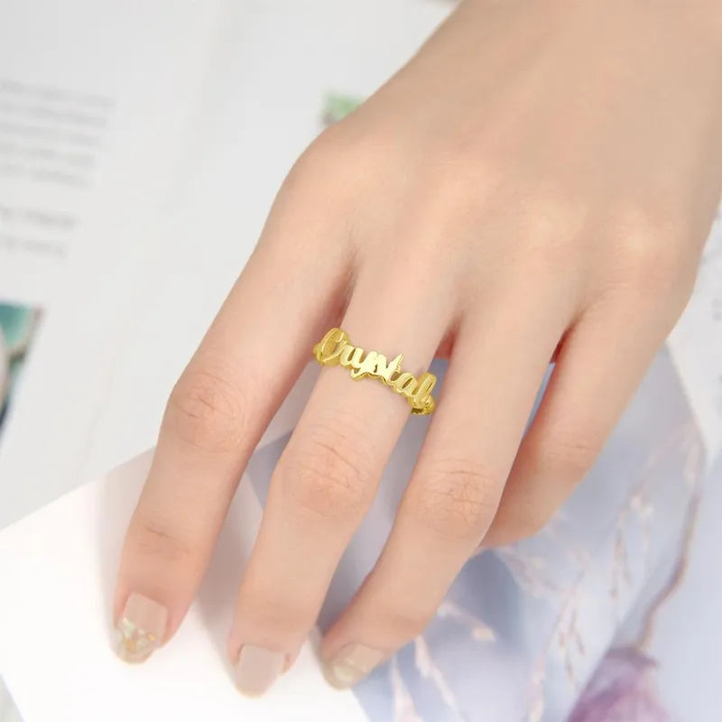 Gold ring with 'Crystal' engraving on a person's finger against a blurred background