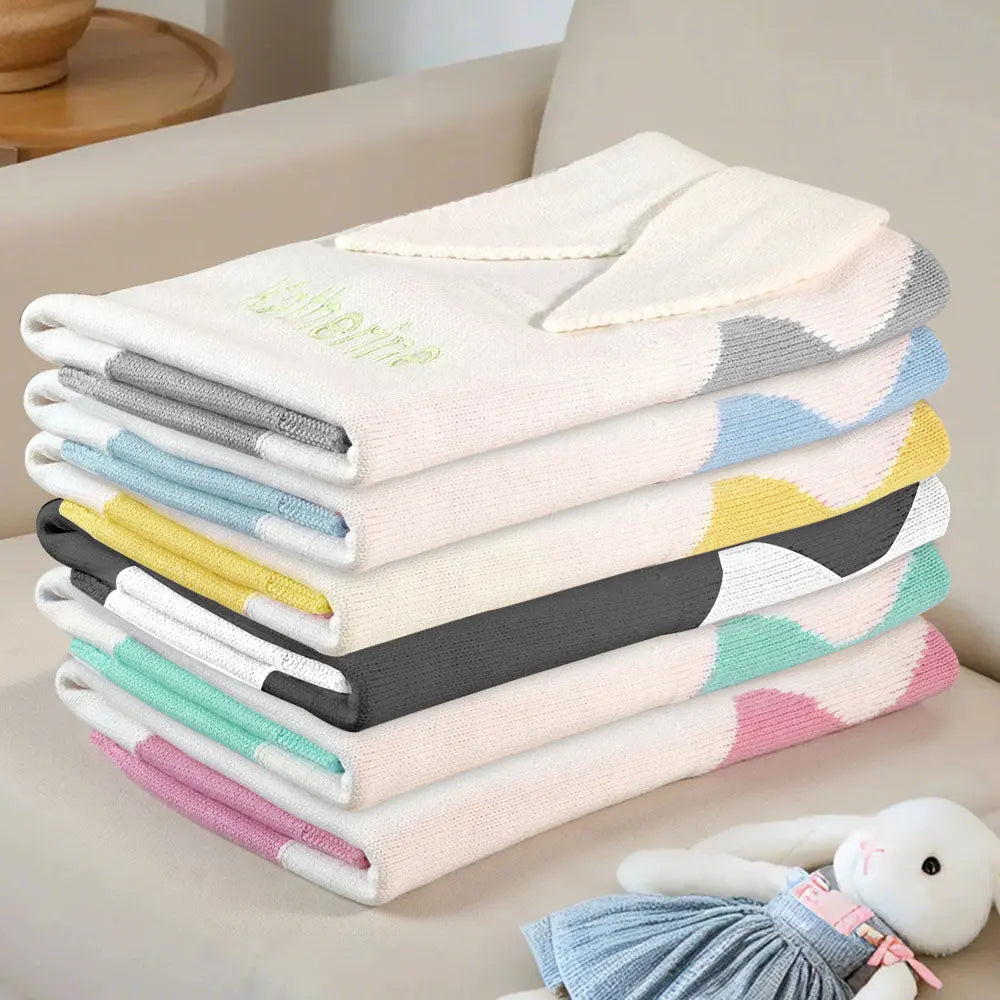 Stack of colorful folded towels on a light surface with a plush toy in the background.