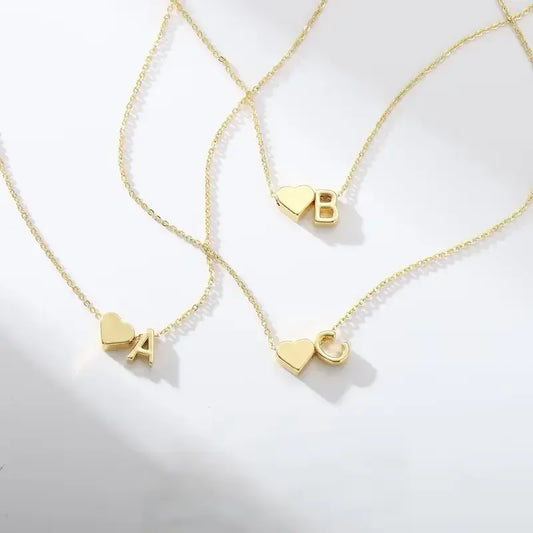 Two gold necklaces with heart-shaped pendants on a light gray background