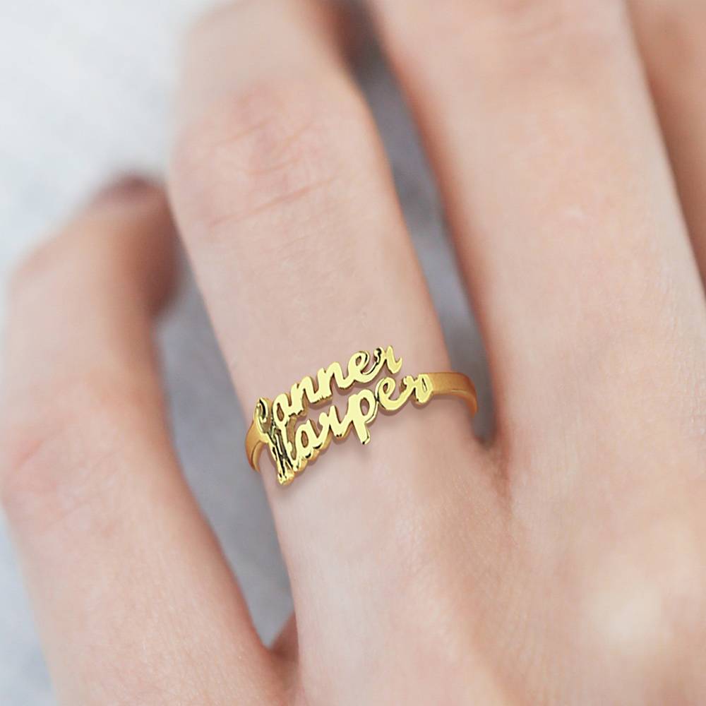 Gold name ring on a finger with a blurred background