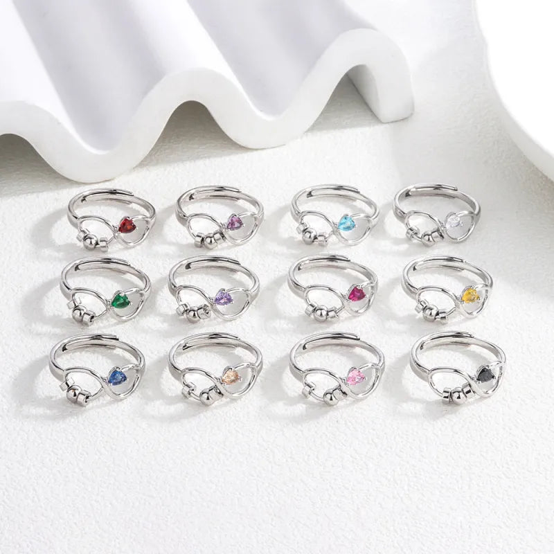 Set of silver rings with colorful gemstones on a white surface