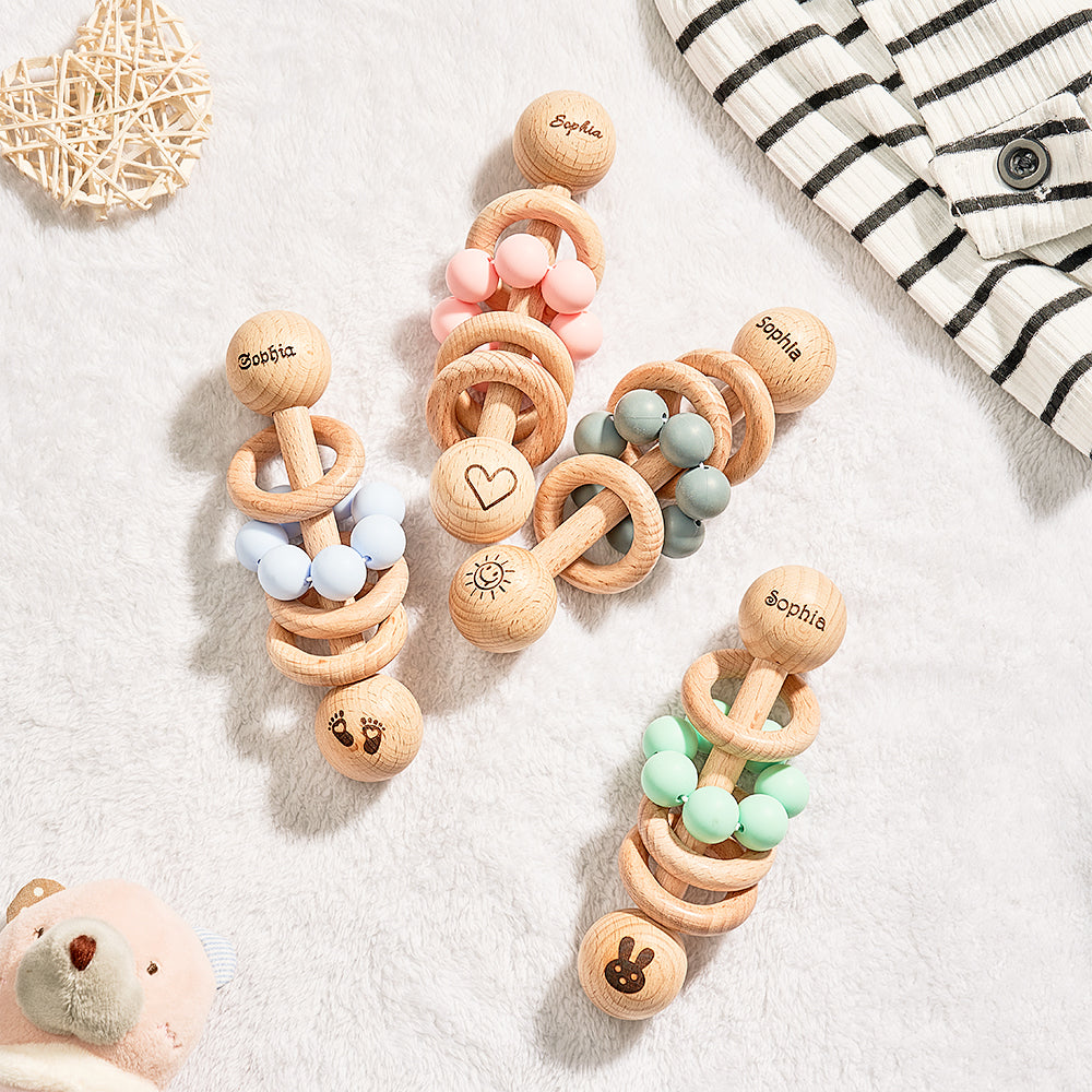 Wooden baby teething rings with colorful beads on a light surface.