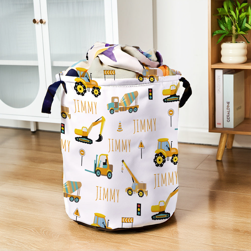 Laundry basket with construction vehicle pattern and 'Jimmy' text on a wooden floor.