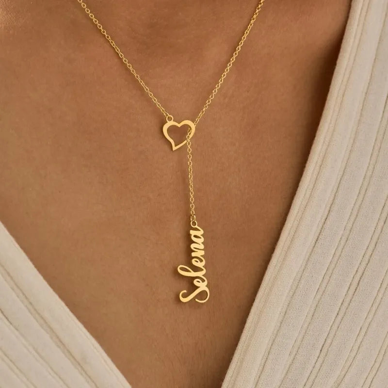 Gold necklace with 'Selenia' pendant on a person wearing a white top.