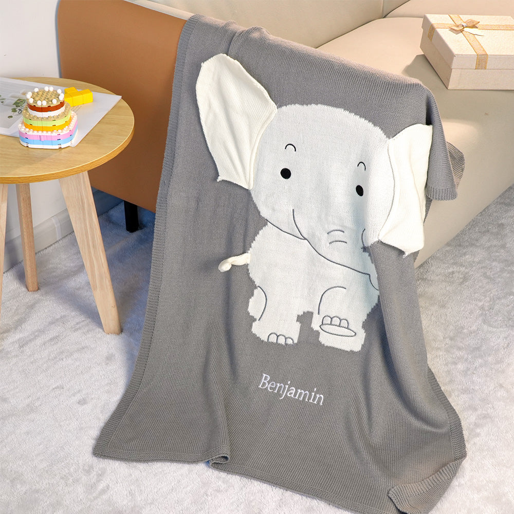 Gray blanket with an elephant design and 'Benjamin' text, draped over a surface.