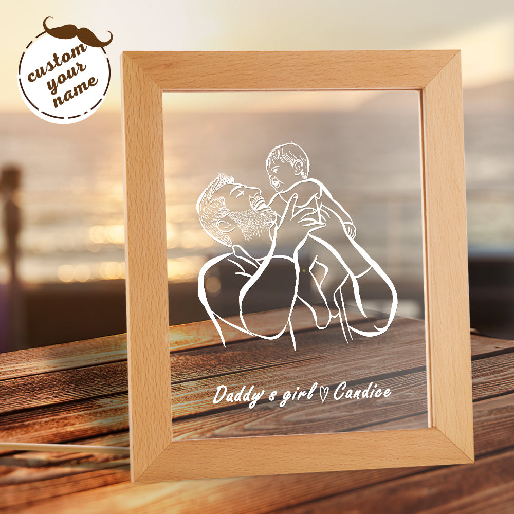Framed artwork of a father and child with 'Daddy's girl' text, on a wooden surface.