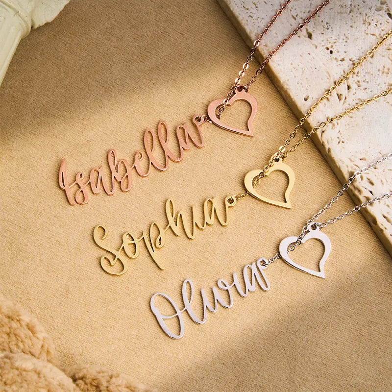 Three name necklaces with heart pendants on a textured surface