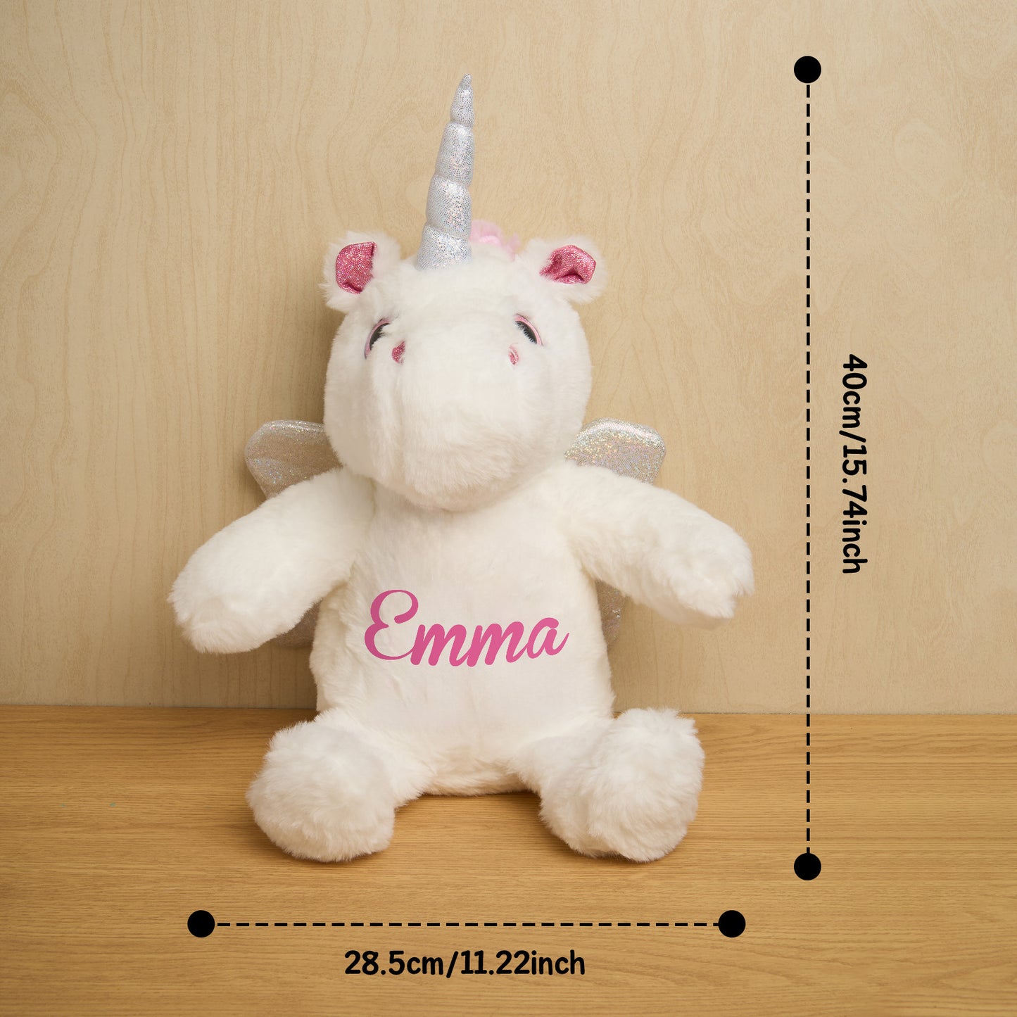 Plush unicorn toy with 'Emma' on a wooden surface and beige wall background