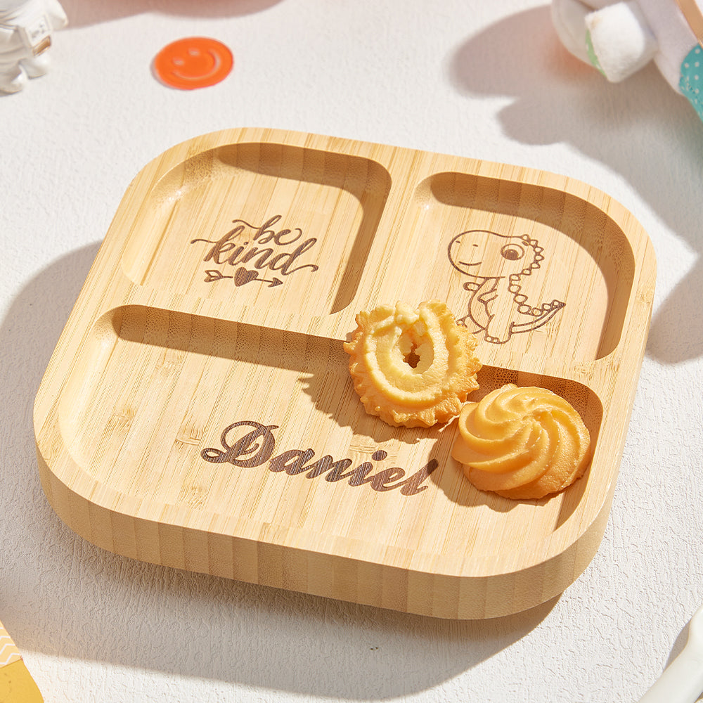 Wooden tray with 'be kind' and a dinosaur illustration, along with cookies on a light background.