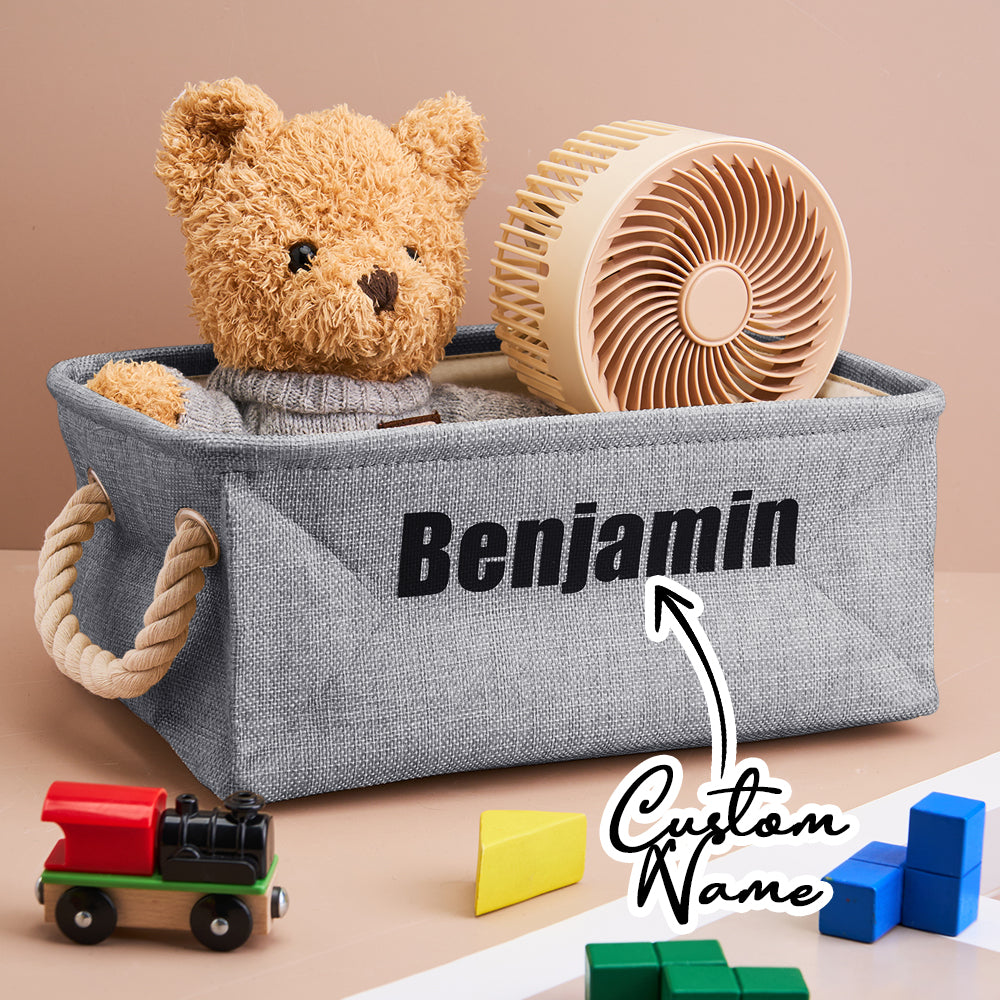 Gray storage bin with a teddy bear, wooden fan, and toys on a beige background