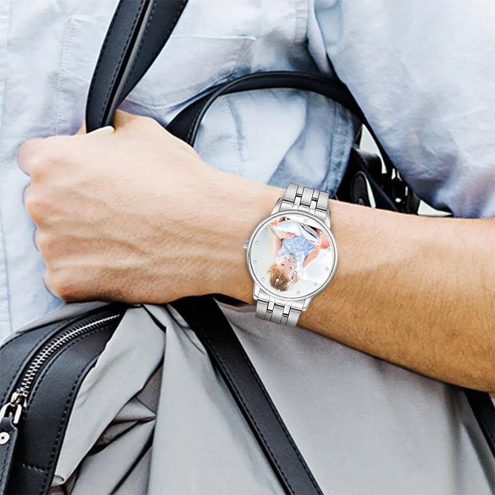 Person wearing a watch with a detailed face, holding a black bag.