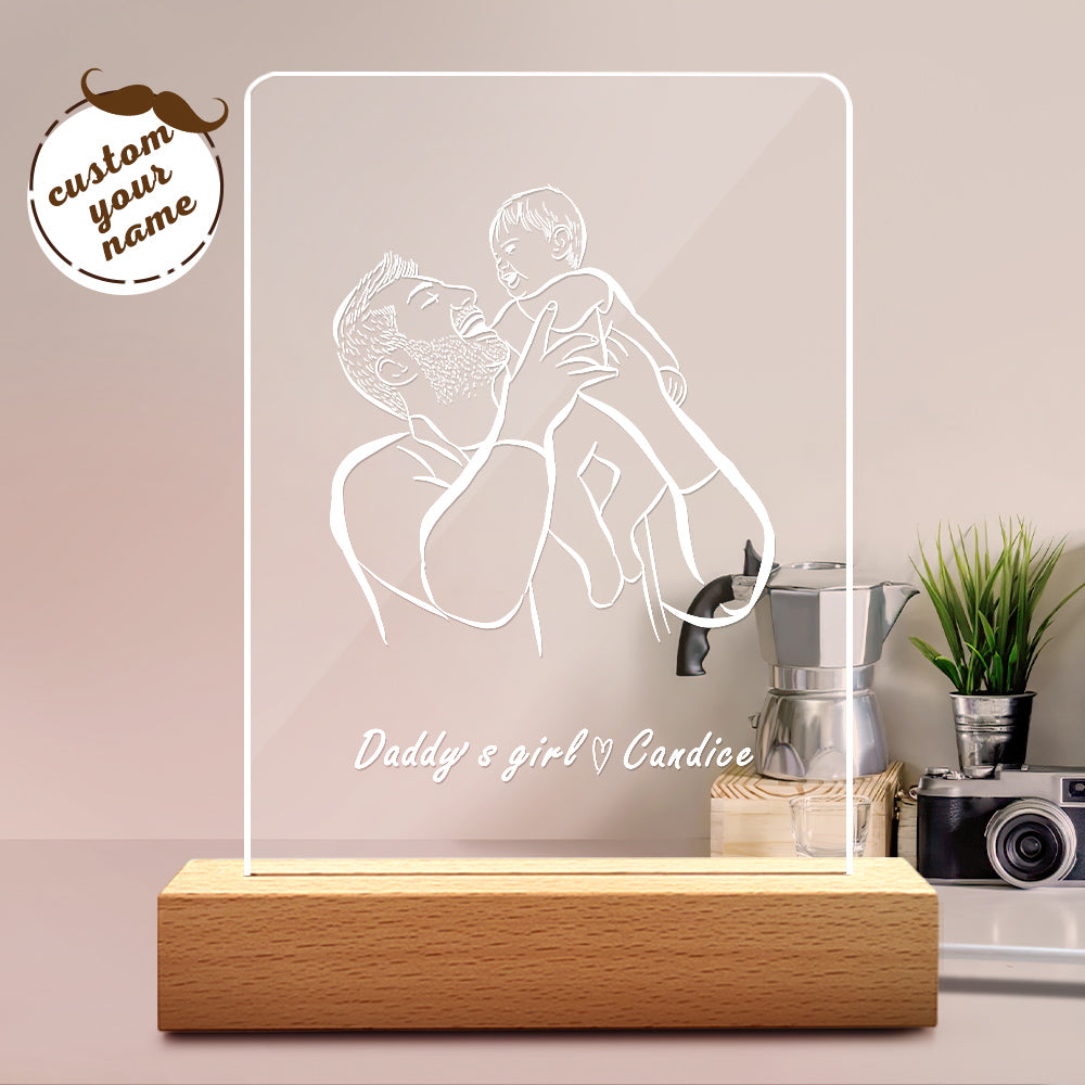 Decorative lamp with a design of a man and woman hugging, placed on a surface with a plant and camera in the background.