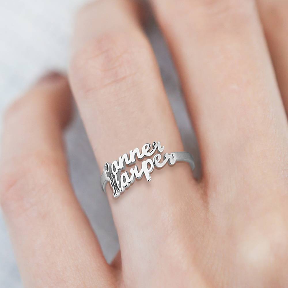 Silver ring with 'Janner Harper' engraving on a finger against a neutral background