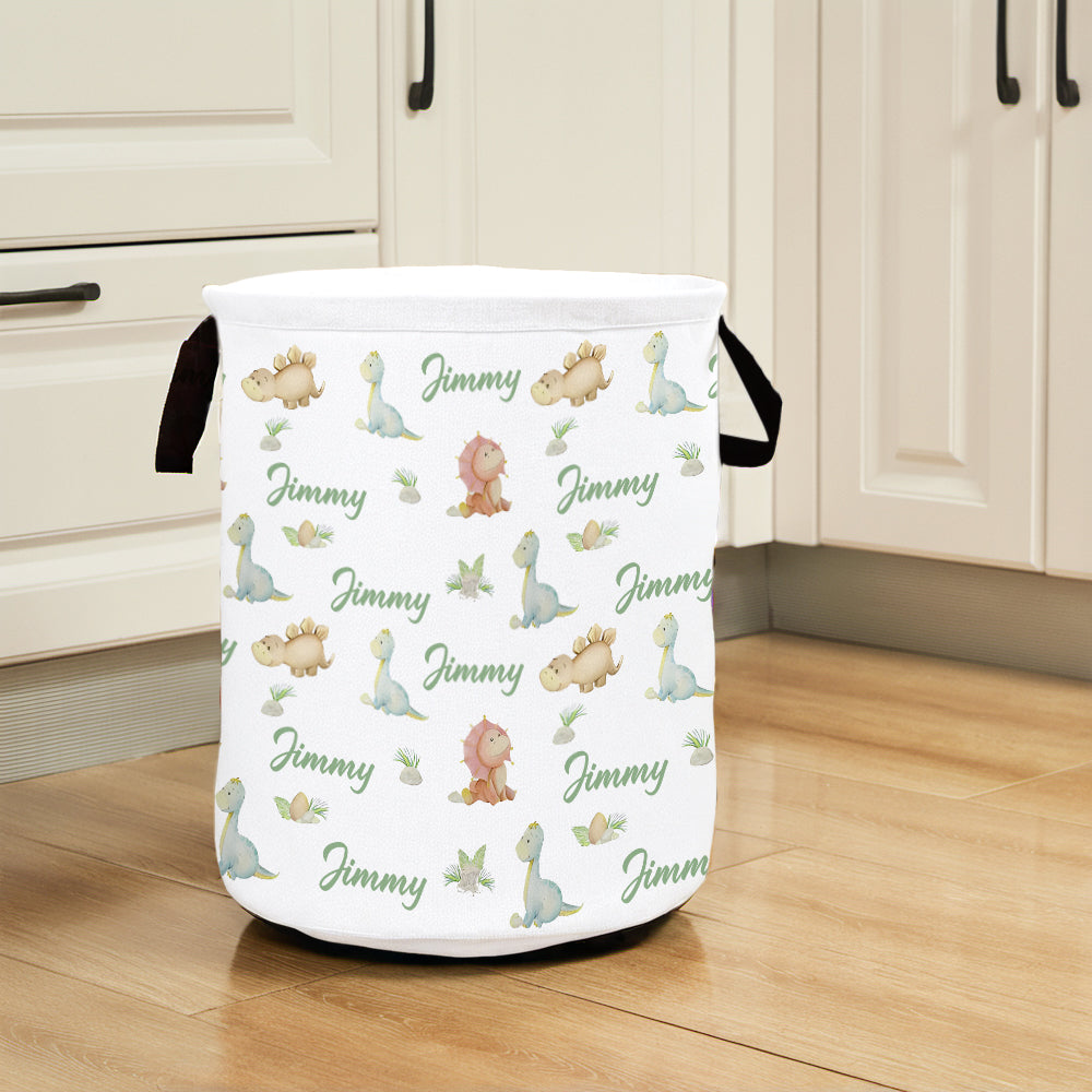 White laundry basket with dinosaur pattern and 'Jimmy' text on a wooden floor.