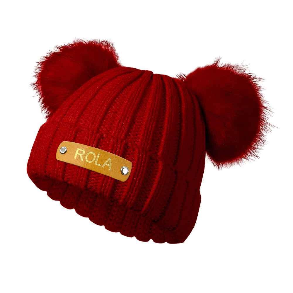 Red knitted beanie with pom-poms and 'ROLA' label on a white background