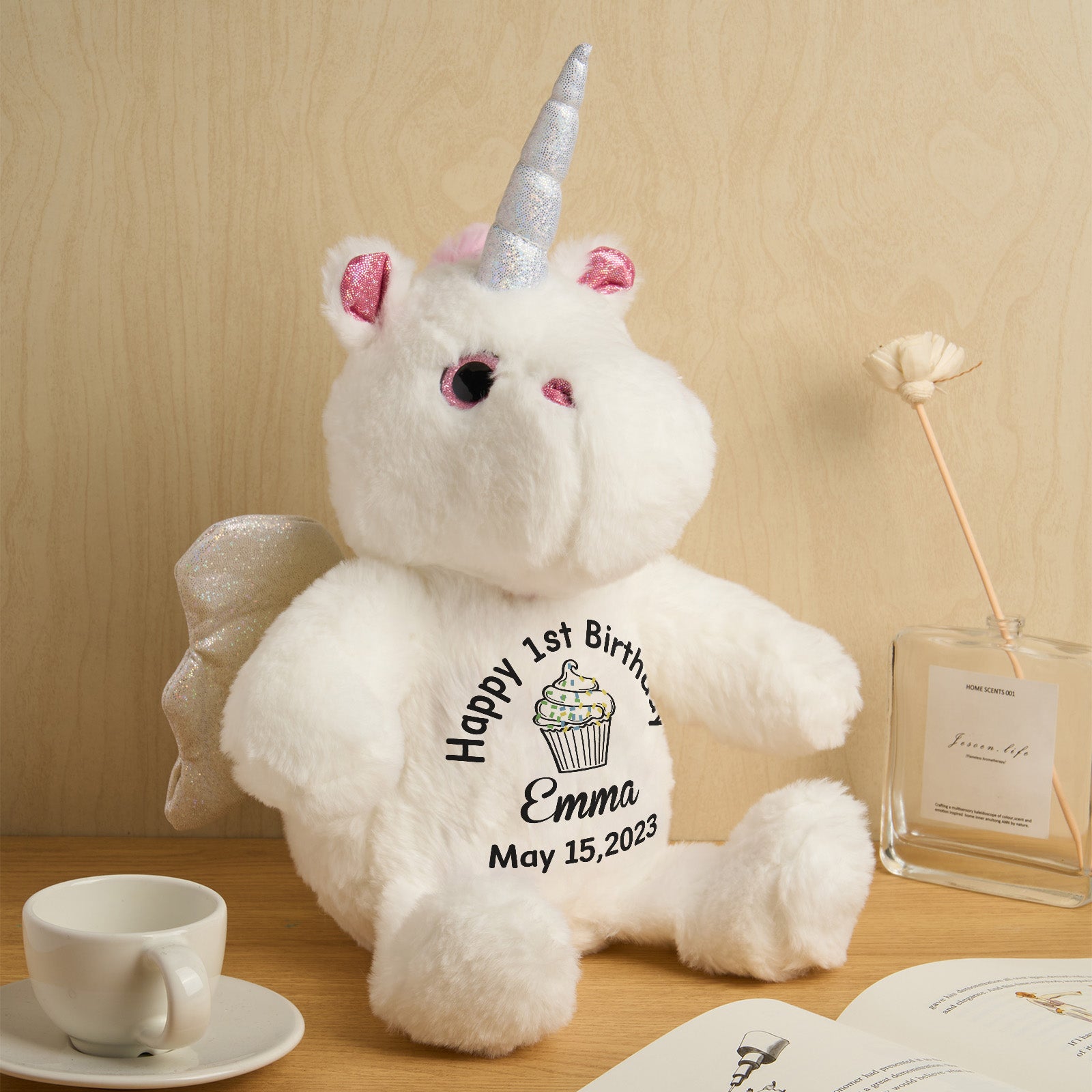 White teddy bear unicorn with personalized text on a wooden surface.