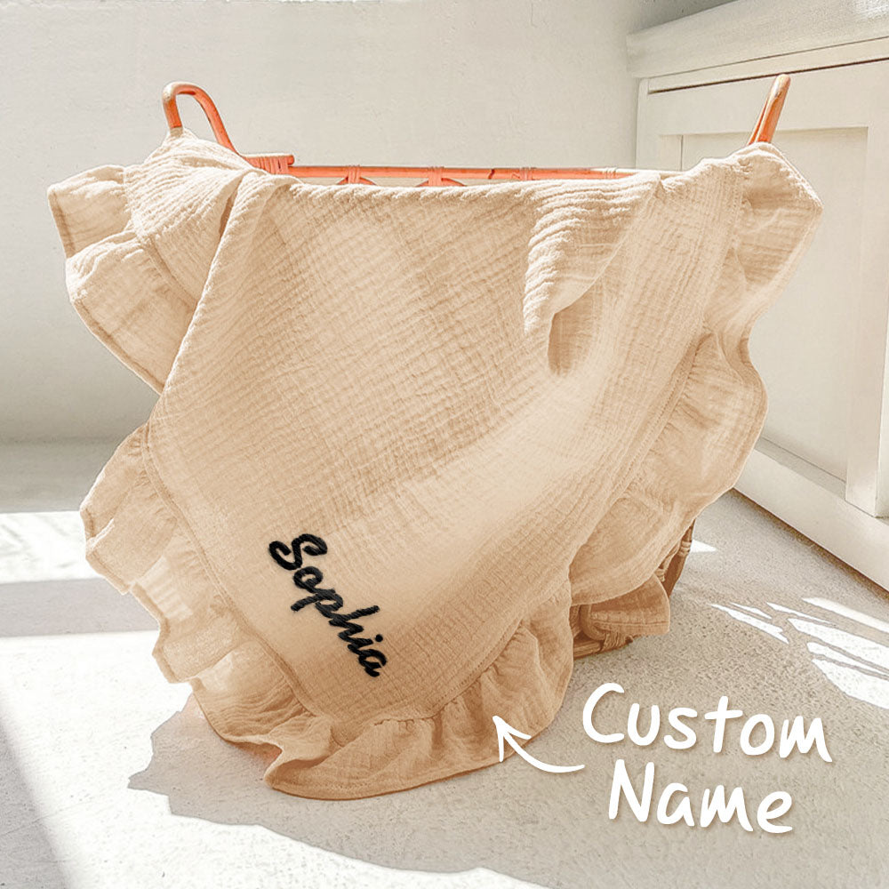 Beige baby blanket with 'Sophia' embroidered on it, draped over a chair.