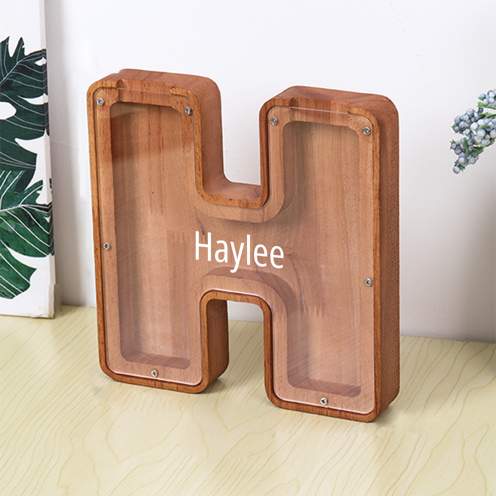 Wooden letter 'H' with 'Haylee' branding on a light wooden floor.