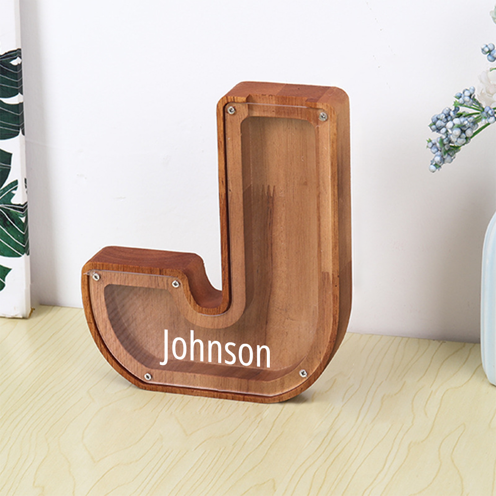 Wooden letter 'J' with 'Johnson' engraved on a light wooden floor.