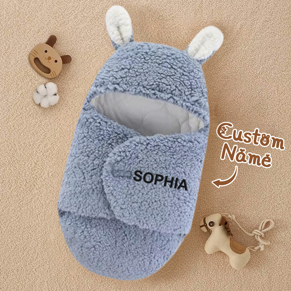 Blue baby outfit with white ears labeled 'SOPHIA' on a beige background