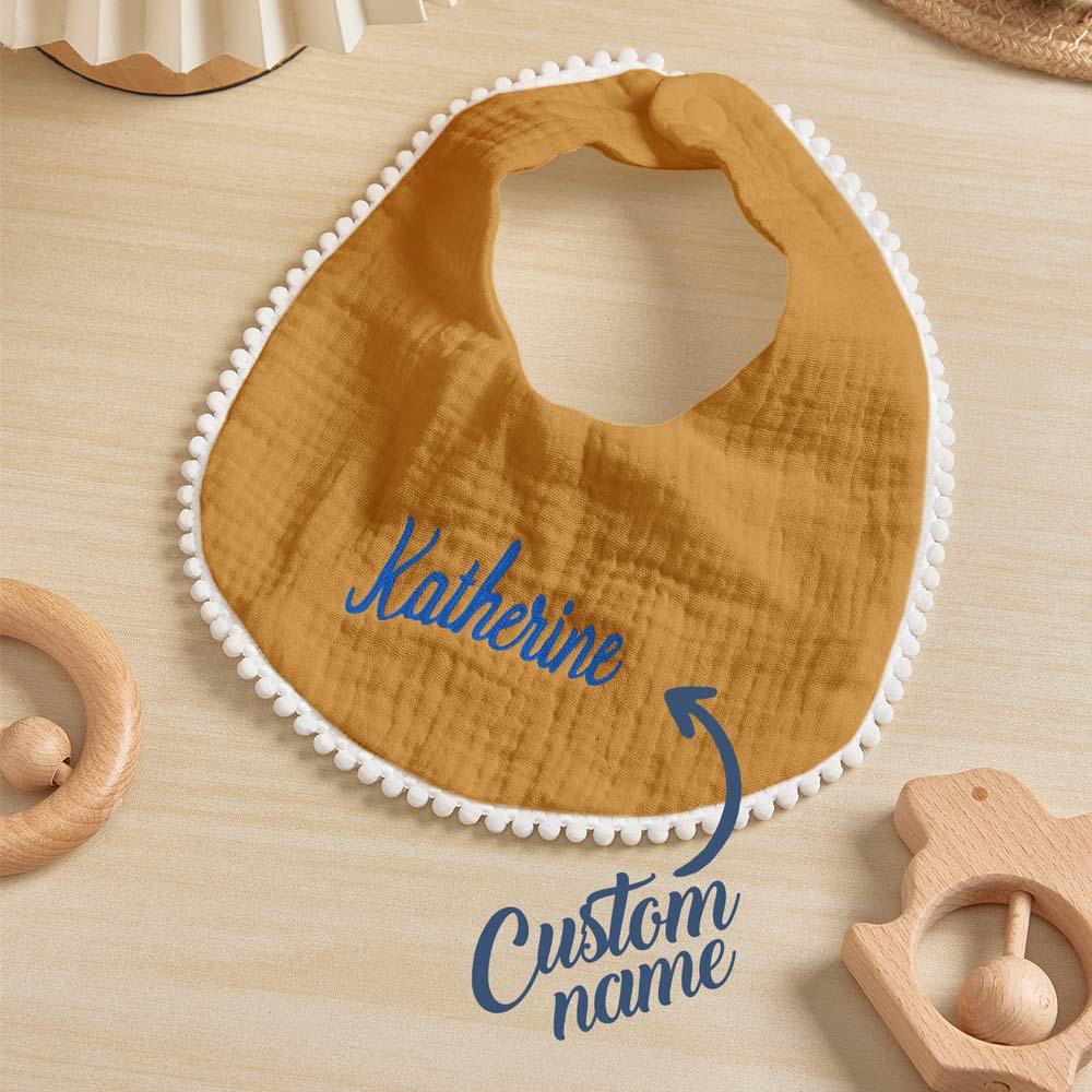 Wooden bib with 'Katherine' and 'Custom name' text on a wooden surface with baby toys.