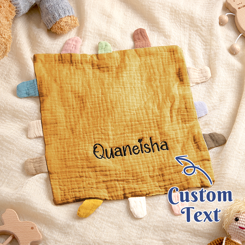 Fabric square with 'Quaneisha' text and wooden toys in the background
