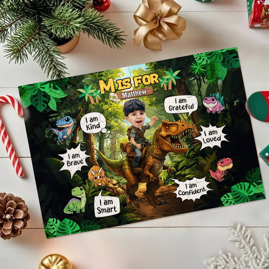 A personalized dinosaur-themed birthday invitation card for 'Mathew' is displayed in a flat-lay Christmas setting. The card features a jungle scene with a child riding a T-Rex, surrounded by speech bubbles with positive attributes like 'I am Grateful', 'I am Brave', and 'I am Smart'.