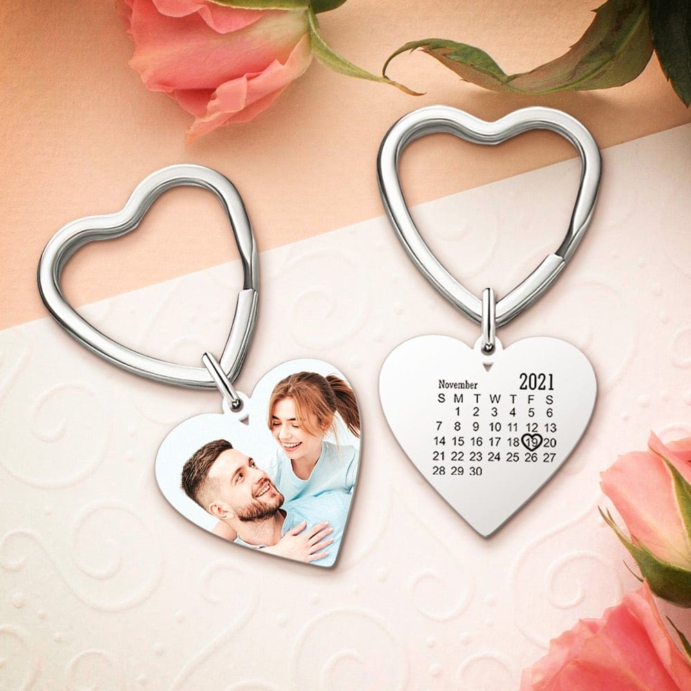 Heart-shaped keychains with a photo of a couple and a calendar for 2021, surrounded by pink flowers.