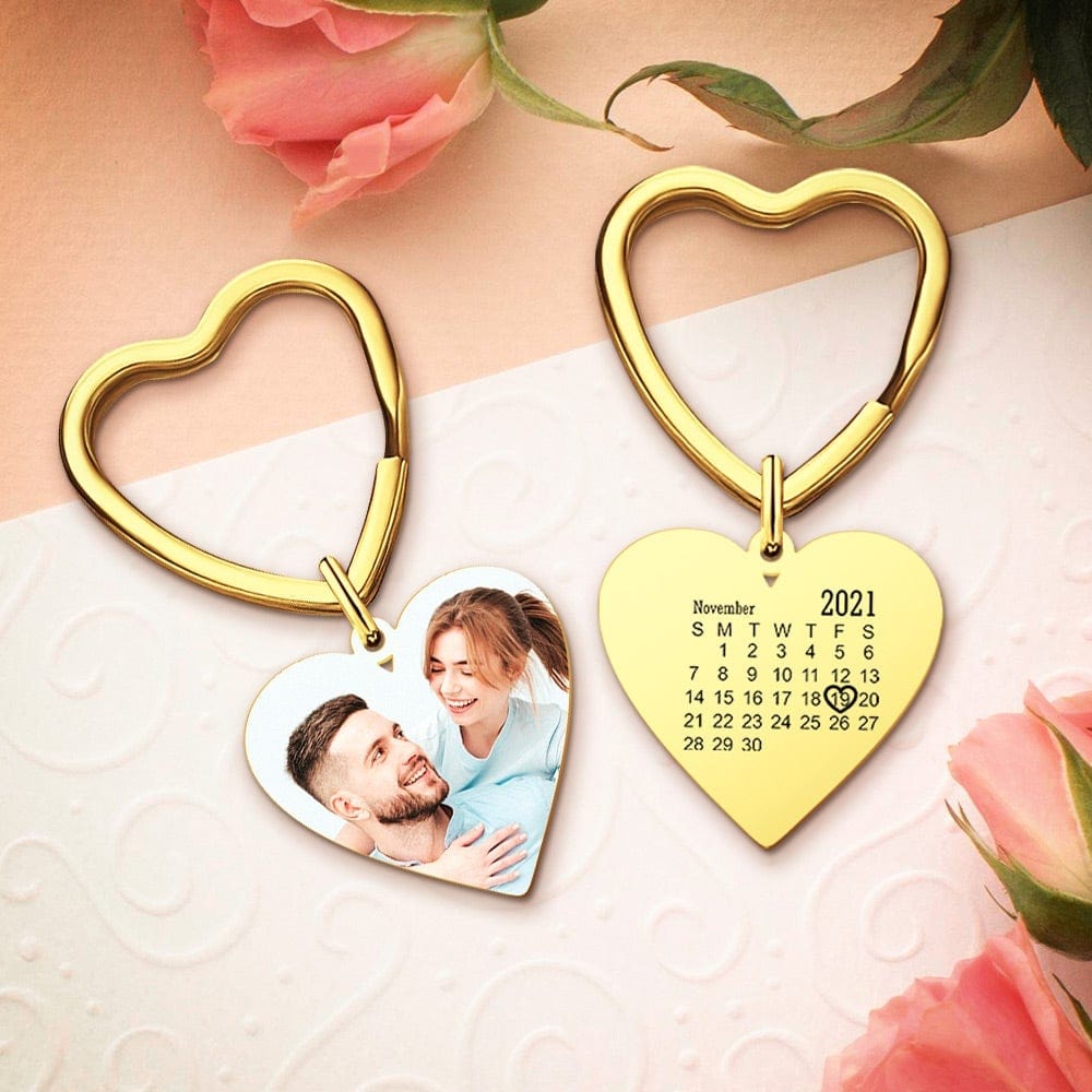 Heart-shaped keychains with a photo and calendar on a soft pink background with flowers.