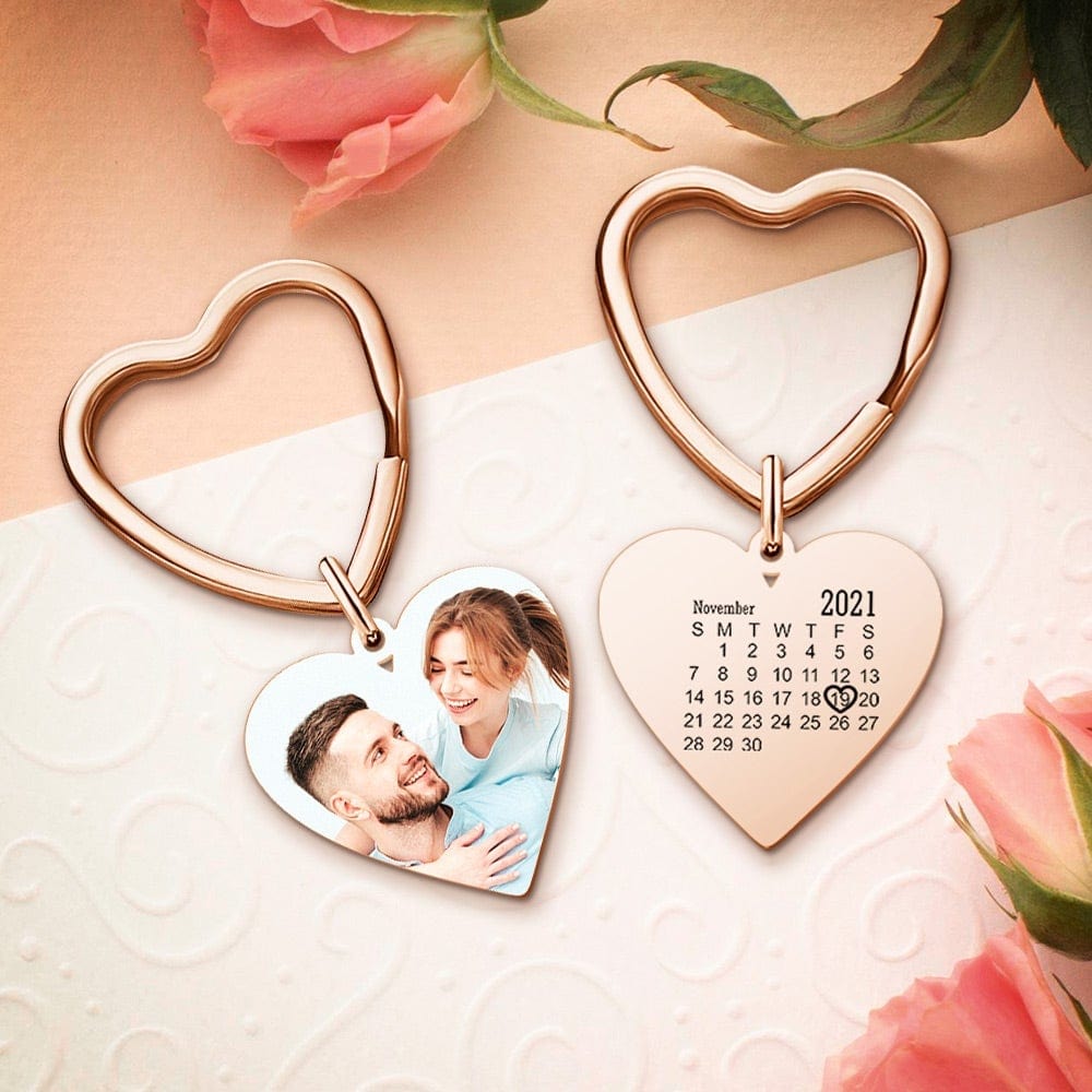 Heart-shaped keychain with a photo of a couple and a calendar on a light background with flowers.