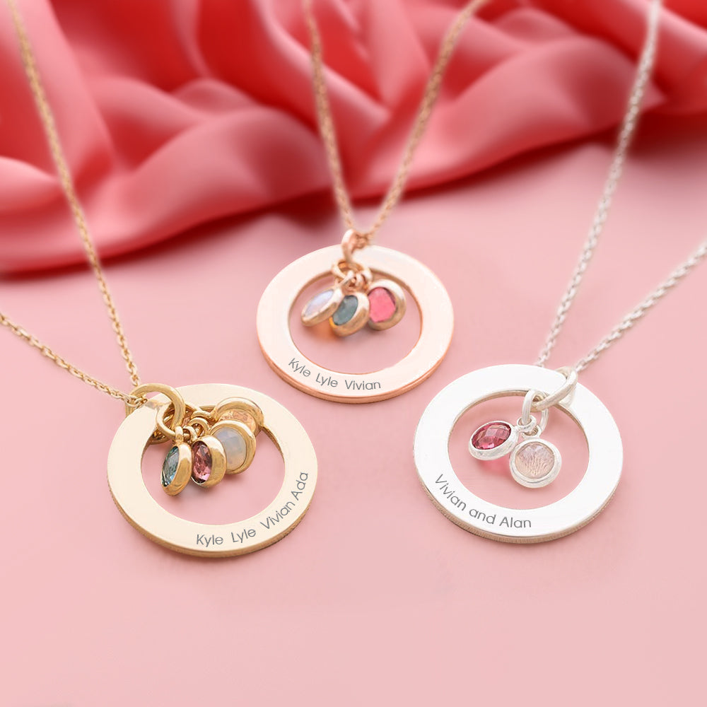 Three personalized necklaces with circular pendants and engraved names on a pink fabric background.