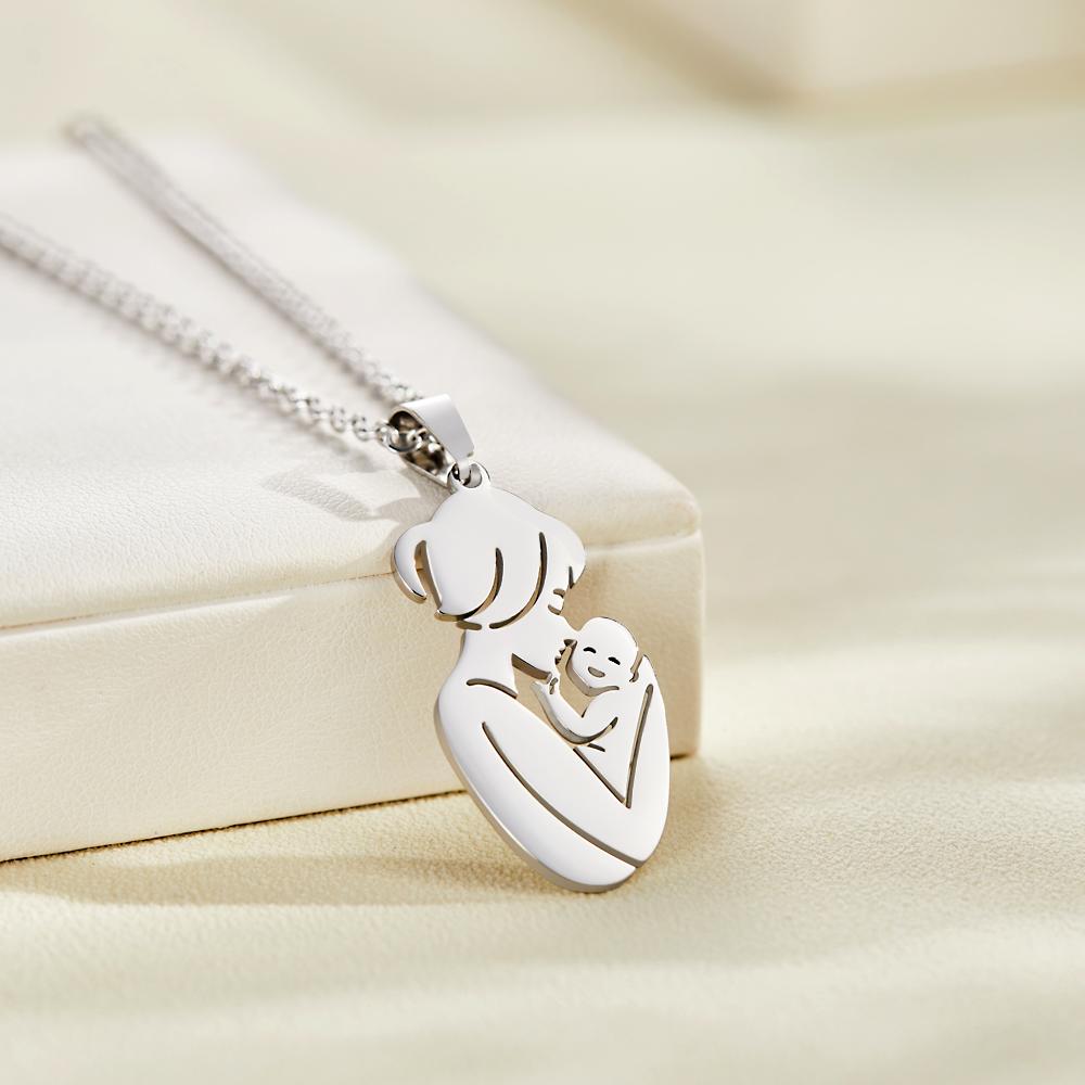 Silver necklace with a pendant of a mother holding a child on a beige background