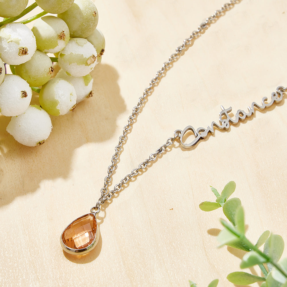 Necklace with a teardrop-shaped pendant on a beige surface with greenery