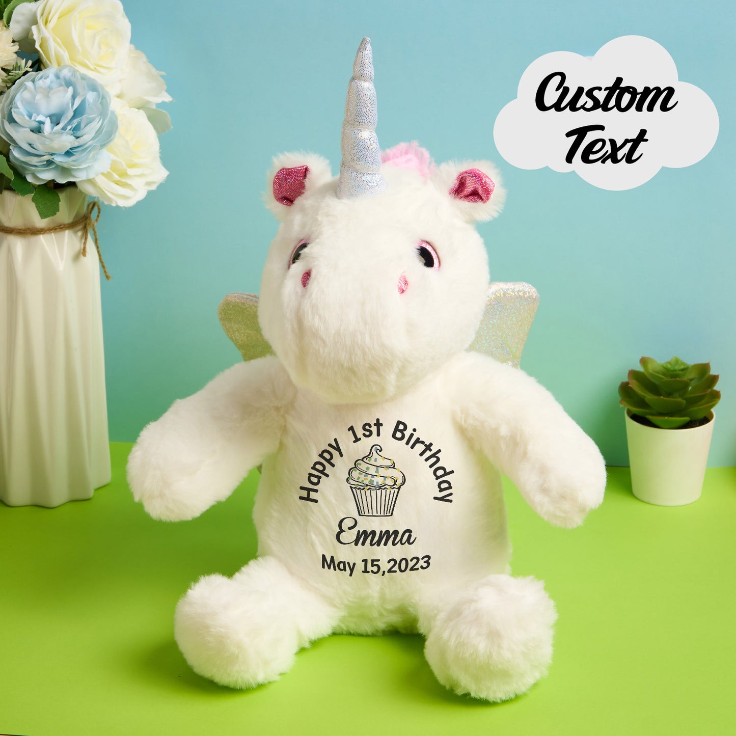 White unicorn plush toy with personalized text on a green surface with decorative elements.