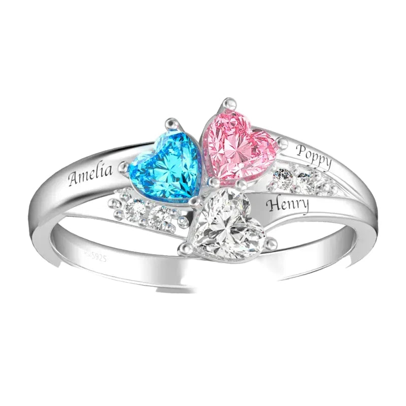 Silver ring with heart-shaped gemstones in blue, pink, and clear, engraved with names.