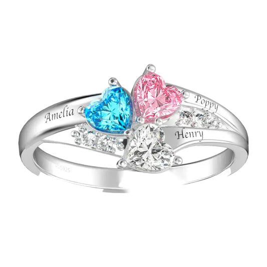 Silver ring with heart-shaped gemstones in blue, pink, and clear, engraved with names.