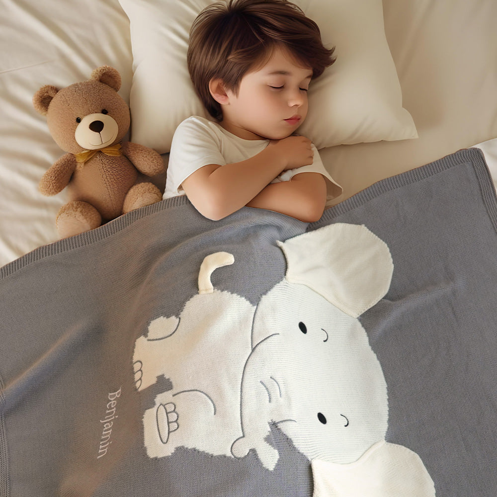 Child sleeping in bed with a teddy bear and a blanket featuring cartoon characters.