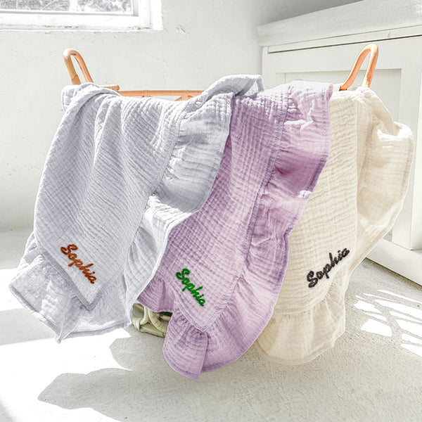 Three baby blankets with 'Sophia' embroidered on them, hanging on a rack.