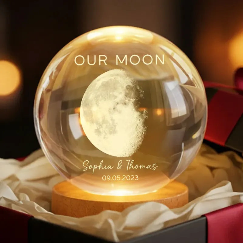 Personalized moon lamp in a glass sphere with 'Our Moon' and names engraved, on a wooden base.