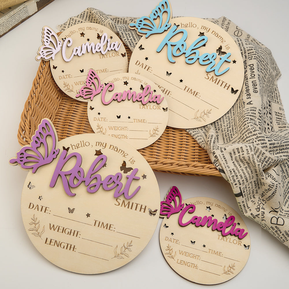 Wooden name tags with butterfly designs and personalized names on a textured surface.