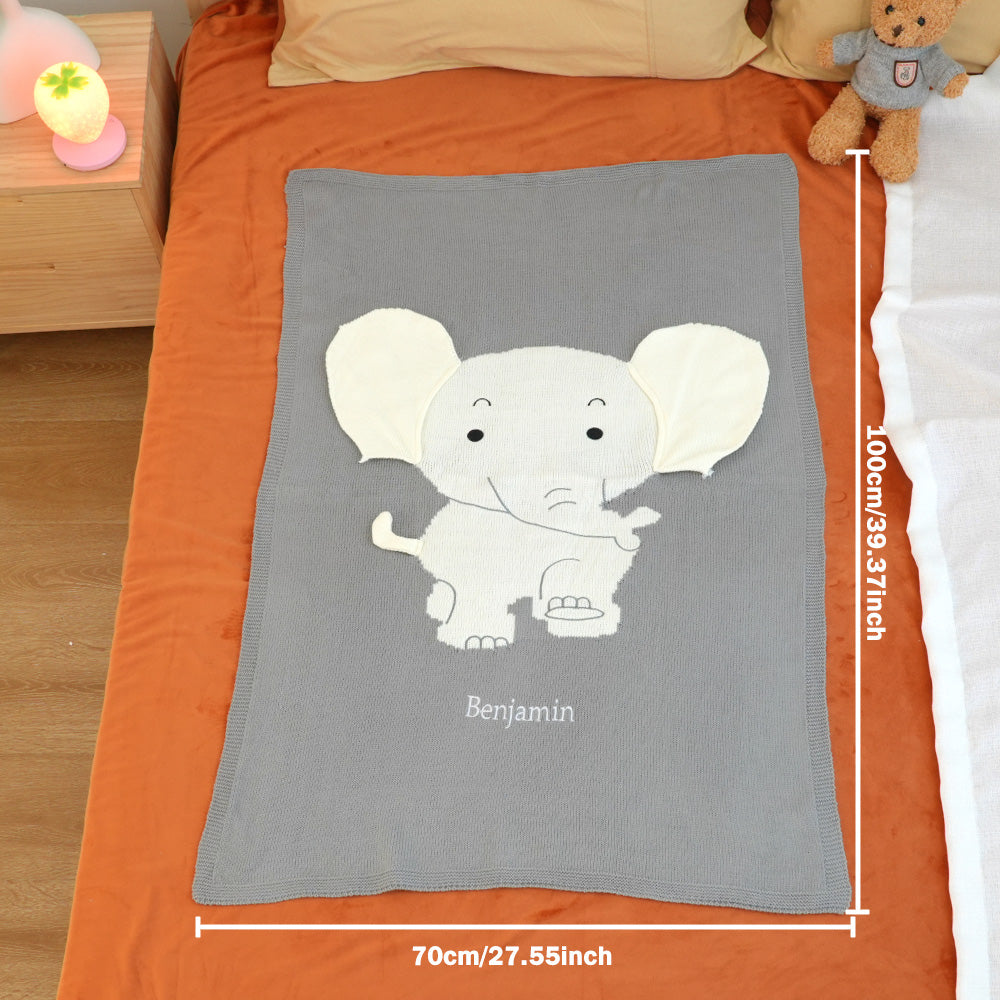 Gray blanket with an elephant design and 'Benjamin' text on a bed.
