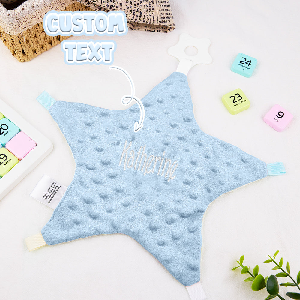 Blue star-shaped pillow with 'Katherine' embroidered on it, placed on a white surface with colorful calendar pages.