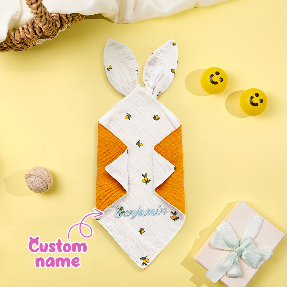 Baby blanket with bunny ears and embroidered name on a yellow background