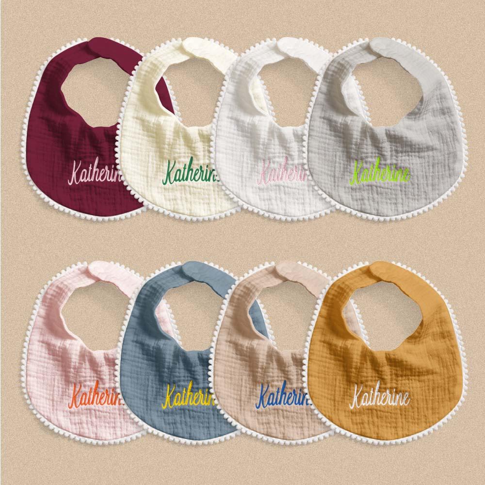Set of colorful baby bibs with 'Katherine' embroidered on them against a beige background.