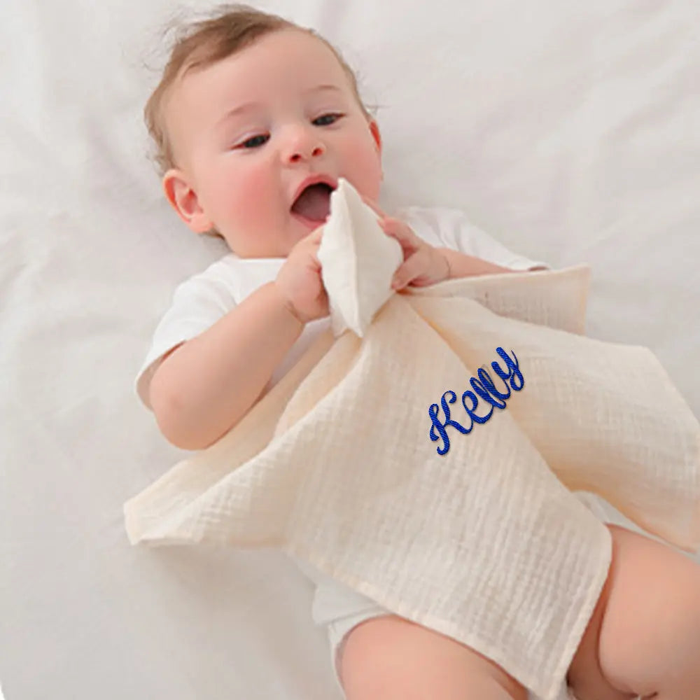 Baby holding a white towel with blue text on a white background
