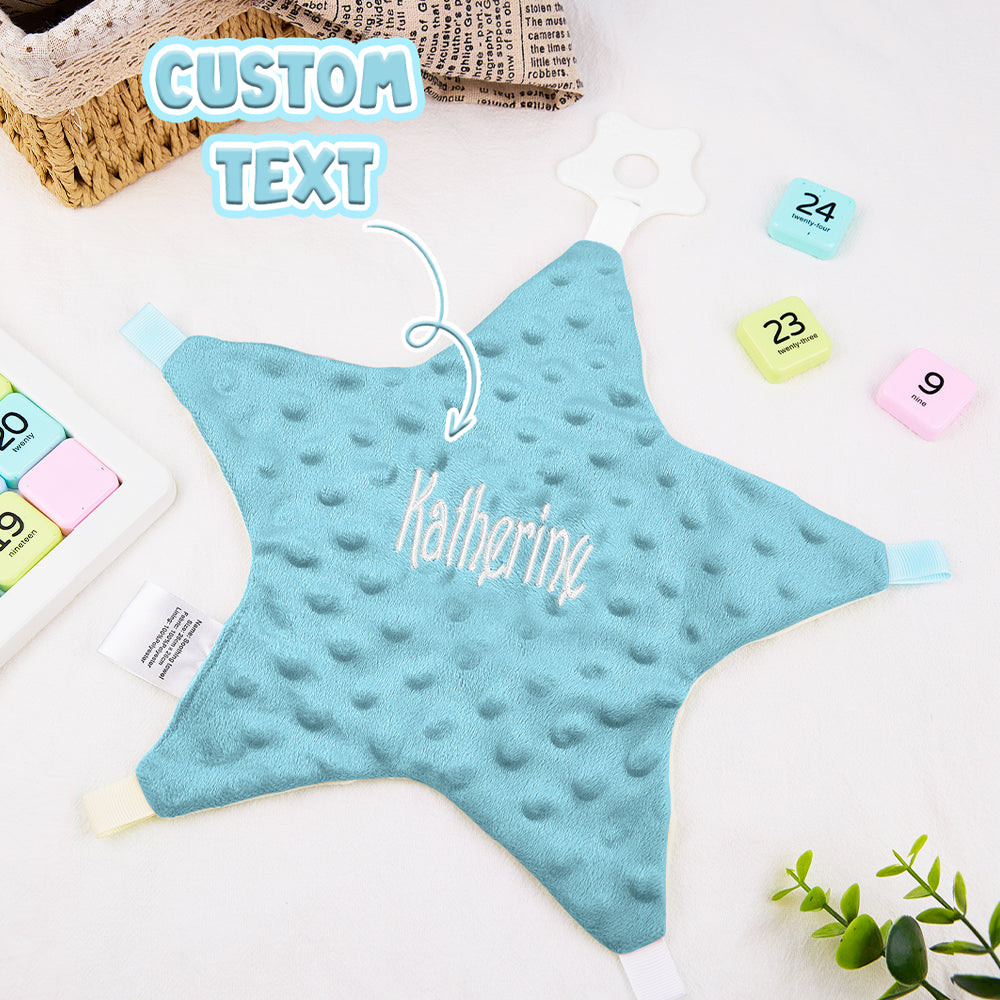 Blue star-shaped pillow with 'Katherine' text on a white surface with stationery items.