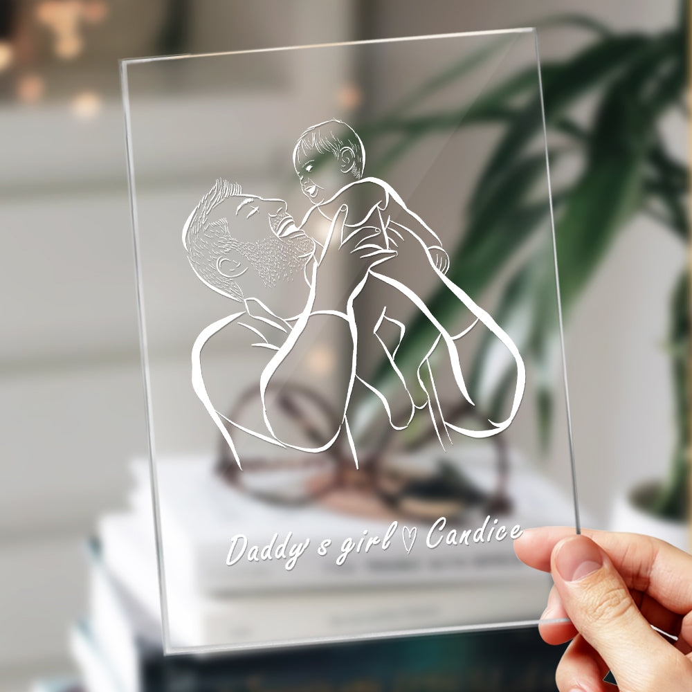 Clear glass plaque with engraved illustration of a father and child, held by a hand.