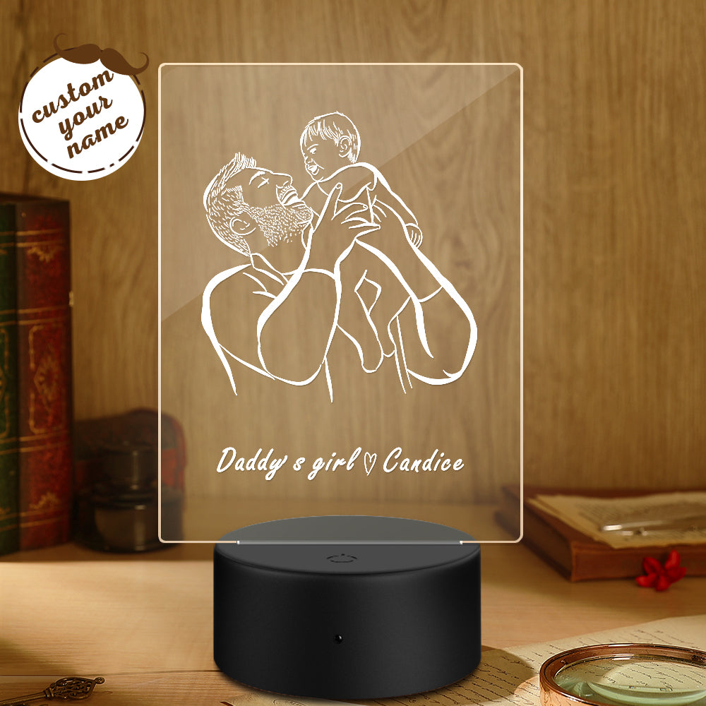 Personalized night light with engraved design of a father and child on a wooden surface.