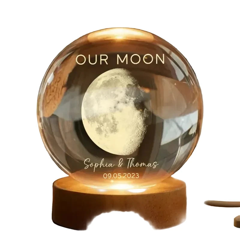 Glass sphere with moon engraving on a wooden base, personalized with names and date.